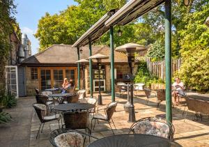 a patio with tables and chairs and people sitting at Santo's Higham Farm Hotel in Alfreton