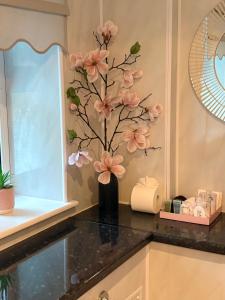 a vase with pink flowers on a counter in a kitchen at All Seasons Bed & Breakfast - Adults Only in Weston-super-Mare +94 photos