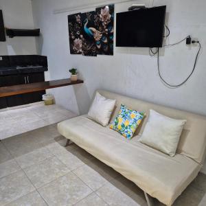 a couch in a room with a tv on the wall at Hostal Casa del Palmar in Santa Marta