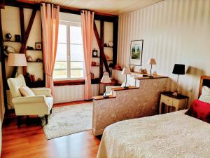 a bedroom with a bed and a chair and a window at Le Clos Lauradière in Cormeilles