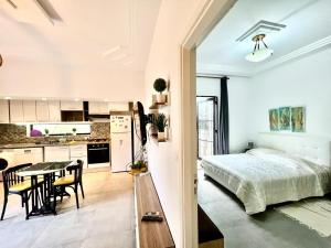 a bedroom and a kitchen with a bed and a table at Work and Wave cosy studio at La Marsa in Douar el Hafey