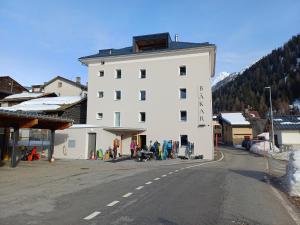 a white building on the side of a street at Camere Osteria Bäkar, Val Bedretto in Bedretto