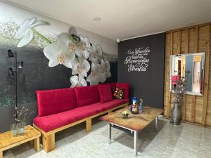 a living room with a red couch and flowers on the wall at Tu Hotel Chía in Chía