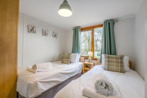 two beds in a room with green curtains at Athelington lodge - Beech in Eye