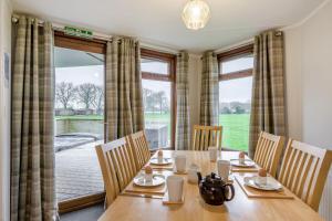a dining room with a table and chairs and a large window at Athelington lodge - Beech in Eye