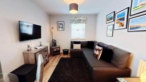 a living room with a couch and a flat screen tv at The Puffin Pad - Part of the The Bay Filey Holiday Village with pool, gym and direct beach access, pub, restaurant, tennis and meadows walks in Filey +44 photos