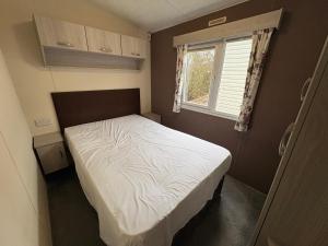 a small bedroom with a bed and a window at Caravan 607 in Clacton-on-Sea