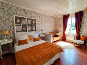 a bedroom with a bed with an orange blanket at Le Clos Lauradière in Cormeilles