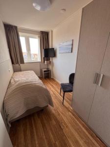a small bedroom with a bed and a window at Appartementen Zeezicht - 3 in Katwijk aan Zee