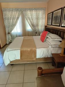 a bedroom with a large bed with a red pillow at Lalakamnandi Guesthouse in Pretoria