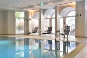 a pool with chairs and tables in a building at Radisson Blu Hotel Schwarzer Bock Wiesbaden in Wiesbaden