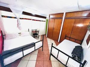 a bedroom with two beds and a table in the background at Uhuru Peak Hostel in Moshi