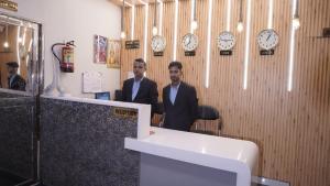 two men standing in a room with clocks on the wall at Hotel Golden Aura Inn in Gwalior