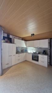 a kitchen with white cabinets and a wooden ceiling at Martina in Saint-Vith