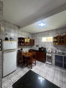 a kitchen with a table and a white refrigerator at Casa de Temporada in Caucaia
