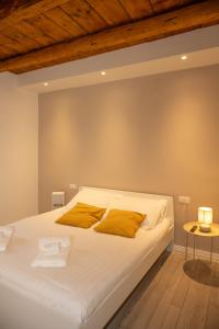 a bedroom with a large white bed with yellow pillows at Dimora del Borgo in Lovere