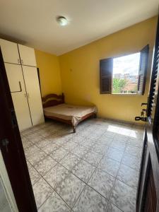 an empty room with a bed and a window at Casa de Temporada in Caucaia