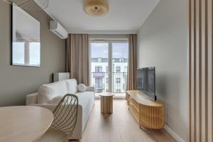 a living room with a couch and a tv and a table at GRANO FLATS Trimare Sztutowo in Sztutowo