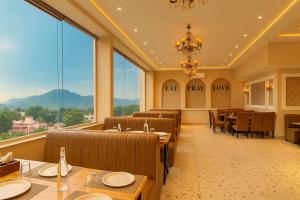 a dining room with tables and chairs and large windows at Hotel Nirvana Palace Near Parmarth Niketan in Rishīkesh +83 photos