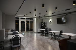 a restaurant with tables and chairs and a flat screen tv at Hotel Nicholas in Chişinău