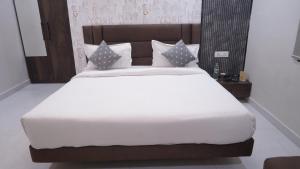 a bedroom with a large bed with white sheets and pillows at Hotel Golden Aura Inn in Gwalior