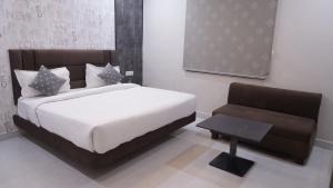 a bedroom with a white bed and a chair at Hotel Golden Aura Inn in Gwalior +3 photos