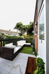 a patio with a couch and a table on top at Bold Coastal Retreat with Boudoir Interiors, Felpham Village in Bognor Regis +3 photos