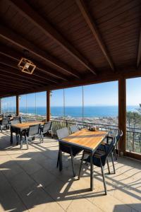 a patio with tables and chairs and a view of the ocean at Gokyuzu Hotel in Edremit