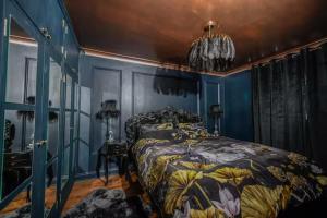 a bedroom with blue walls and a bed with a floral bedspread at Bold Coastal Retreat with Boudoir Interiors, Felpham Village in Bognor Regis