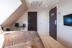 a attic bedroom with a bed and a flat screen tv at Hotel Bella Ciao in Harderwijk