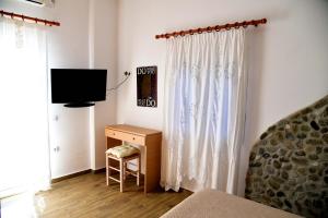 a bedroom with a television and a desk with a chair at Stone Apartments Kythnos in Kanala