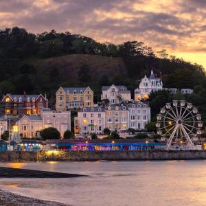 a city with a ferris wheel in front of a town at St. Hilary Guest House in Llandudno +44 photos