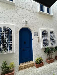 a blue door on a white building with two windows at Dar Dahbia in Asilah