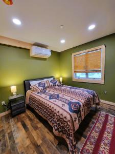 a bedroom with a bed with green walls and a window at Cold Brook Lodge - 2 and 3 Bedroom Luxury Apartments in Lake Placid