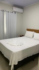 a bedroom with a white bed with a white curtain at Executive Hotel Aguas lindas GO in Macacos