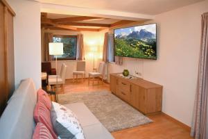 a living room with a couch and a tv on the wall at Riederhof in Leogang