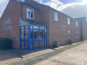 a brick building with a blue door on the side of it at Castle Sleeper in Corby