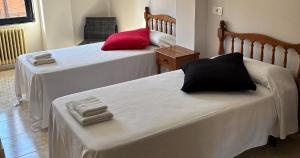 a room with two beds with white and red at DORMERO Hotel y Albergue Sahagun in Sahagún +4 photos