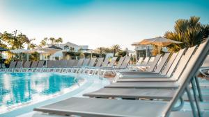 a row of lounge chairs next to a swimming pool at BLUESEA Alyssa Suite Hotel in Playa Blanca