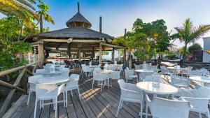 a restaurant with white tables and chairs on a wooden deck at BLUESEA Alyssa Suite Hotel in Playa Blanca