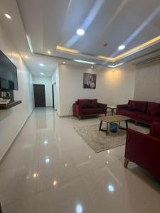 a living room with red couches and a table at ثار بارك للشقق المخدومة in Qushayya