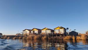 a row of houses on a dock next to the water at Uros & Titicaca Sunset Comfort Floating cabins in Puno