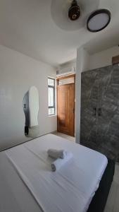 a bedroom with a large white bed with a shower at Bahari Home in Nyali