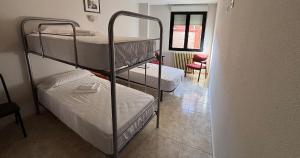 a room with two bunk beds and a chair at DORMERO Hotel y Albergue Sahagun in Sahagún