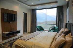a bedroom with a large bed and a large window at HOGS Panorama - Manali in Manāli