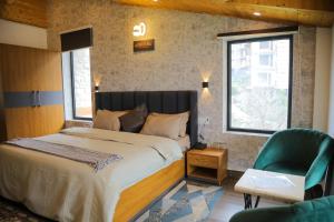 a bedroom with a large bed and a green chair at HOGS Panorama - Manali in Manāli +50 photos