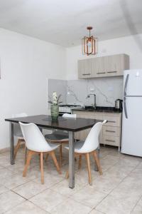 a kitchen with a black table and white chairs at VL Apart in Villa Regina