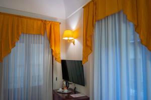 a bedroom with blue and yellow curtains and a television at Hotel La Plumeria in Cefalù +70 photos
