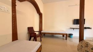 a room with a bed and a chair and a tv at Athiratha Living in Malpe