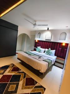 a bedroom with a large bed with a red headboard at Hotel Gandharva Executive in Pune